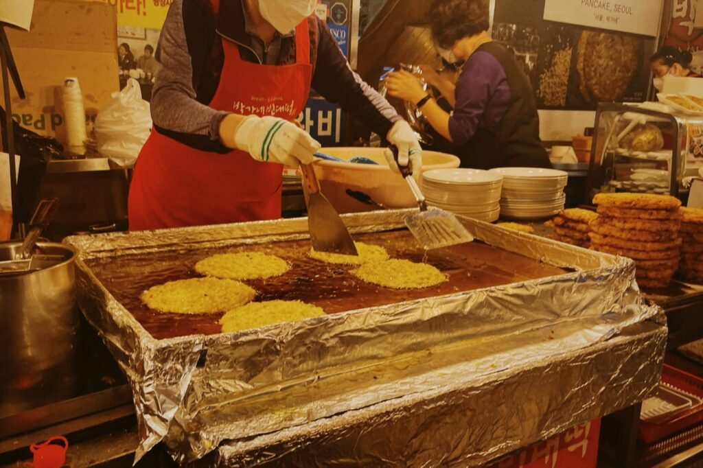 Mung-bean pancakes frying on a griddle at Gwangjang Market