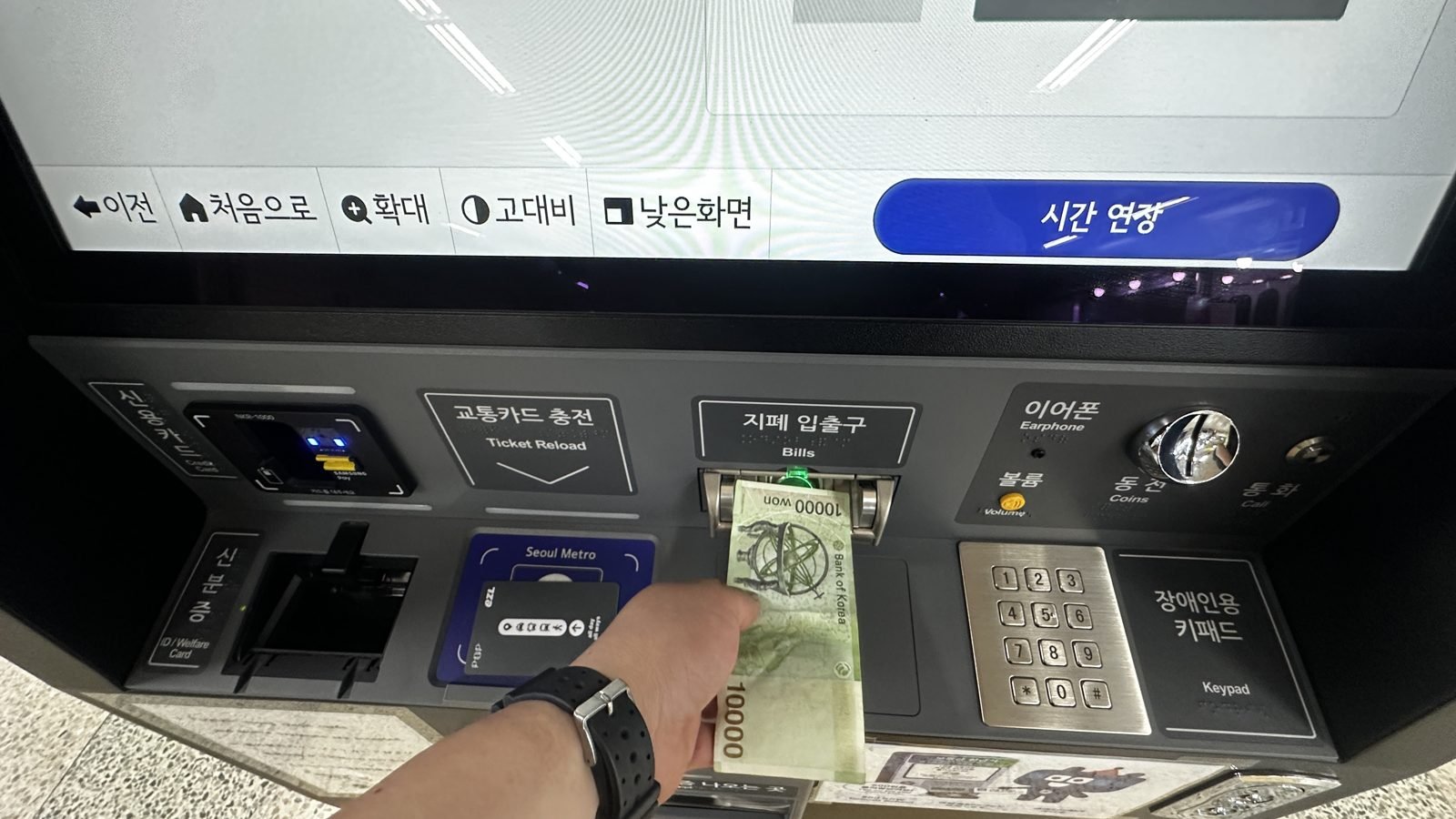 Hand resting a transit card on a station machine reader to recharge it
