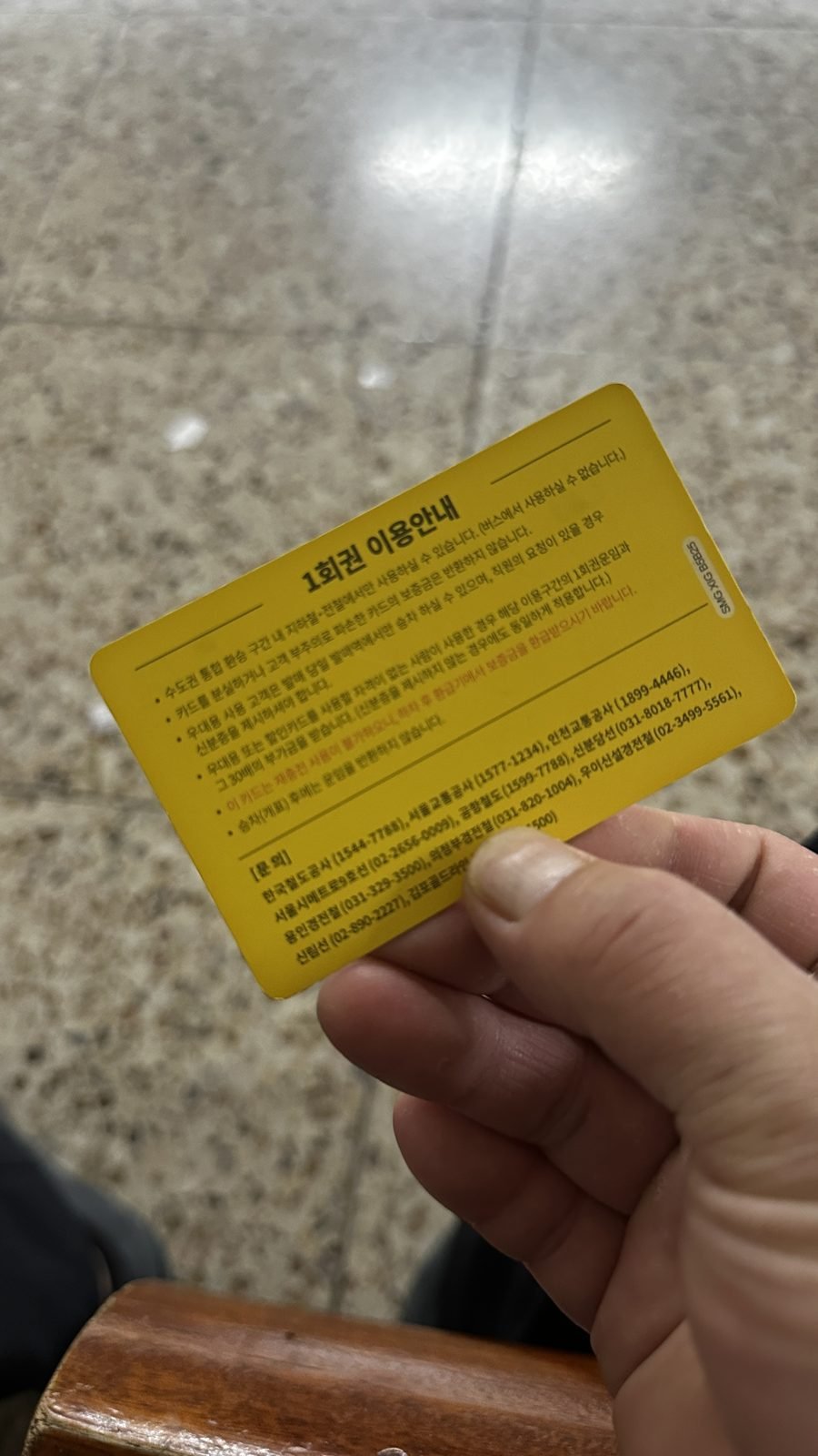 A yellow single-journey Seoul subway ticket card held in hand
